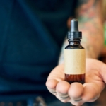 Damlalıklı küçük bir cam serum şişesini tutan bir el