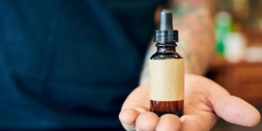 Damlalıklı küçük bir cam serum şişesini tutan bir el