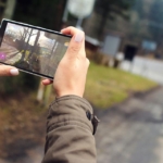 İki eliyle tuttuğu akıllı telefonla açık havada fotoğraf çeken bir kişinin elleri