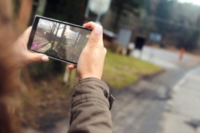 İki eliyle tuttuğu akıllı telefonla açık havada fotoğraf çeken bir kişinin elleri