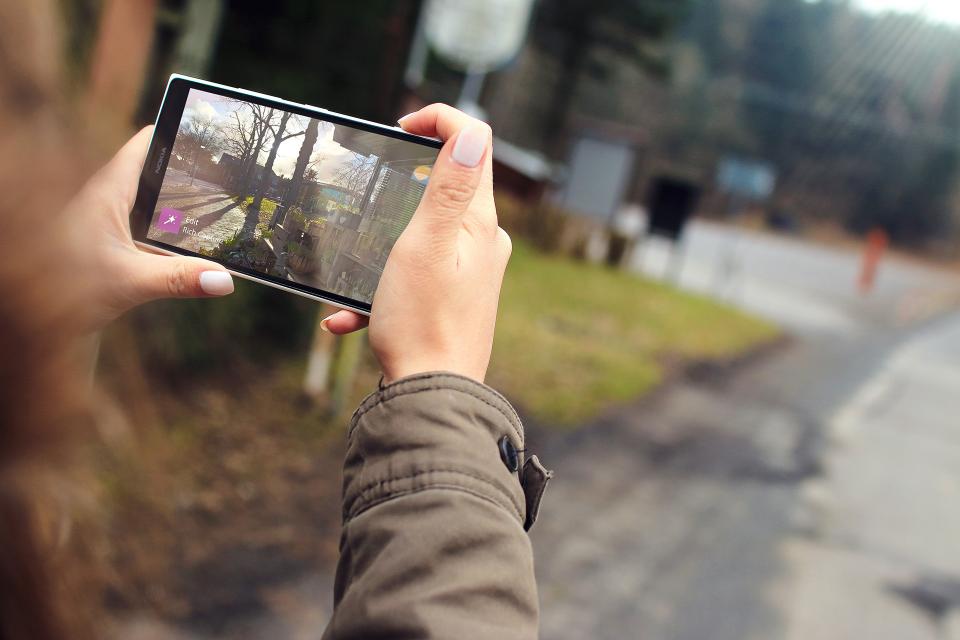 İki eliyle tuttuğu akıllı telefonla açık havada fotoğraf çeken bir kişinin elleri