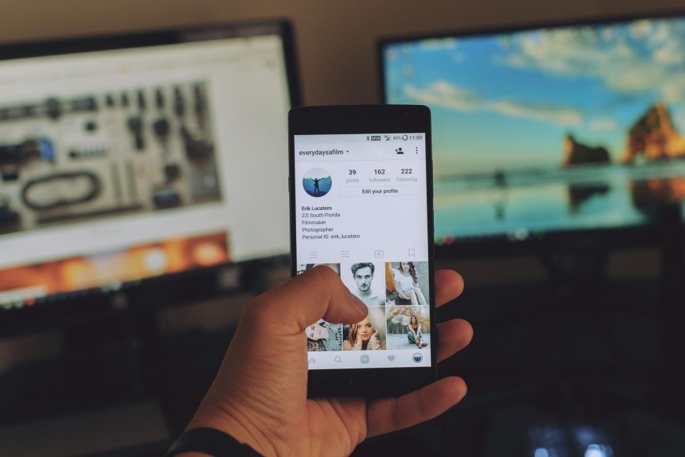 Elinde sosyal medya akışı açık bir akıllı telefon tutan kullanıcı