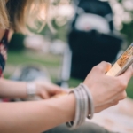 Oturan bir kişinin iki eliyle tuttuğu akıllı telefon yakından görülüyor