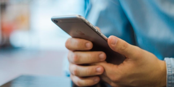 İki eliyle akıllı telefon tutan ve ekrana dokunan bir kişinin elleri