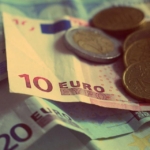 Üst üste duran euro banknotları ve üzerlerindeki madeni paralar
