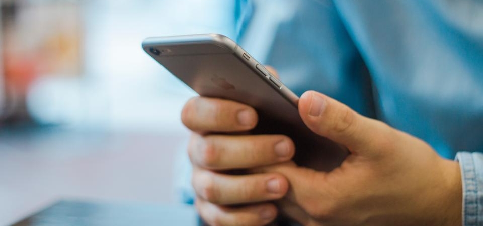 İki eliyle akıllı telefon tutan ve ekrana dokunan bir kişinin elleri