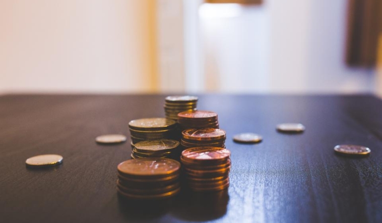 Koyu renkli bir masa üzerinde üst üste dizilmiş madeni para yığınları