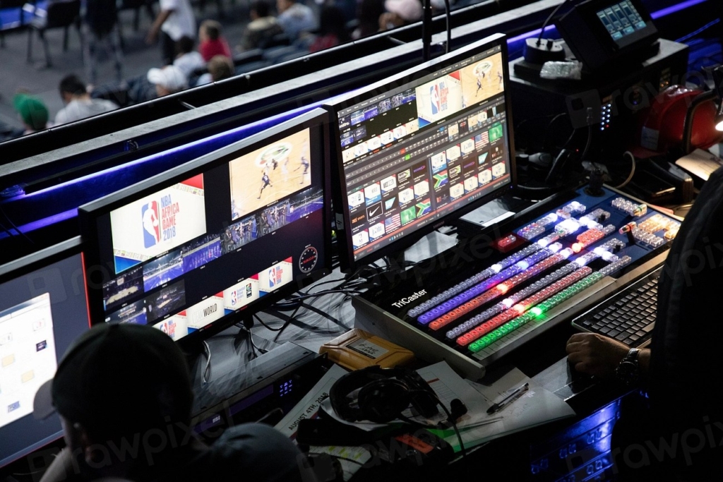 Karanlık bir odada birden fazla monitörün açık olduğu bilgisayar masası